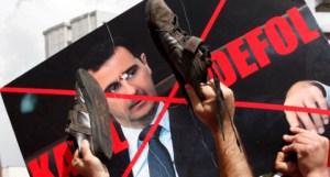 Protesters use their shoes to hit a defaced poster of Syria's President Bashar Al-Assad during a demonstration to express solidarity with Syria's anti-government protesters in front of the Syrian embassy in Ankara June 10, 2011. The words on the poster read: "Murderer. Go away". REUTERS/Umit Bektas (TURKEY - Tags: POLITICS CIVIL UNREST IMAGES OF THE DAY)